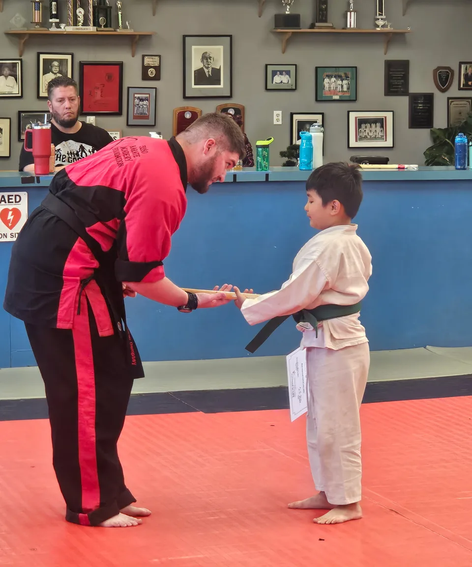Instructor guiding a young student through a martial arts technique